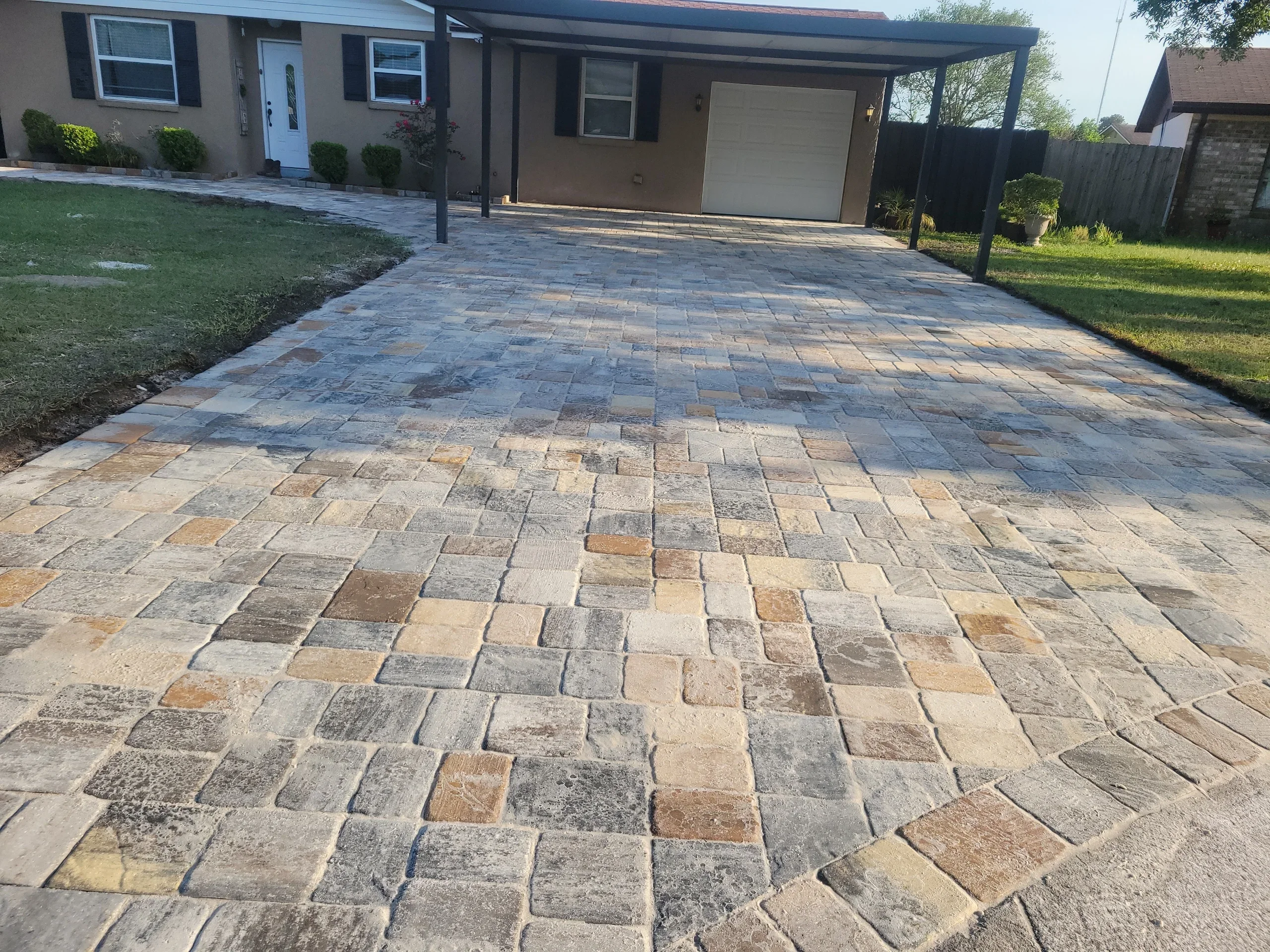 Multi-colored permeable paver driveway with running bond pattern installed in front of residential home